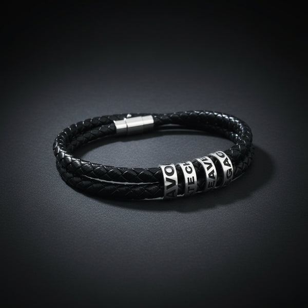 A black braided leather bracelet with silver-toned cylindrical beads featuring white lettering, displayed on a clean white background.