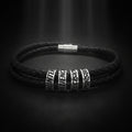 A black braided leather bracelet with silver-toned metal spacers engraved with words including HUNTER, MATHEMATICS, PRECISION, and PURSUIT.