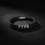 Double-wrap braided black leather bracelet with silver engraved beads reading HUNTER PATIENCE PRECISION PURSUIT on dark matte surface
